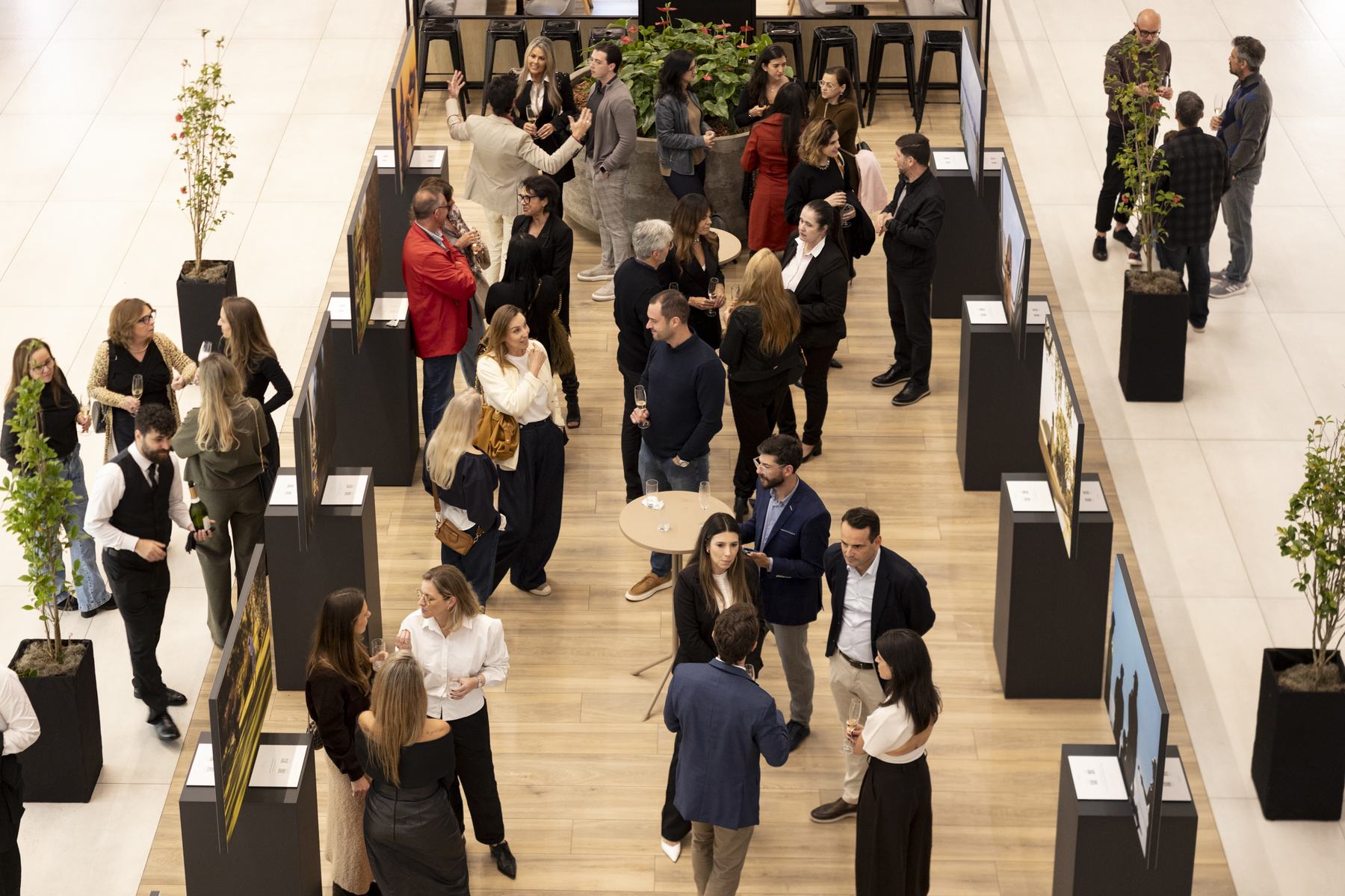 Vista do alto da exposição, com o público circulando entre as fotografias