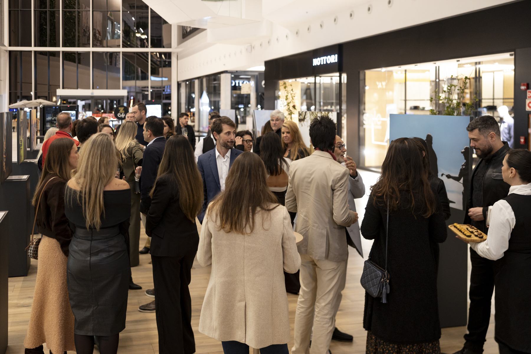 Convidados conversando entre os painéis da exposição na noite de abertura