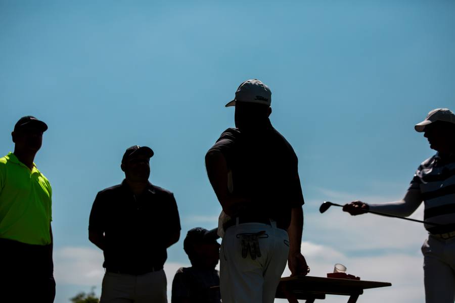 Jogadores de golfe em silhueta conversando no fim da tarde